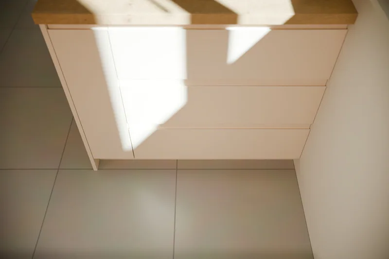 Handleless island drawers with recessed grips, in sunlight from the window